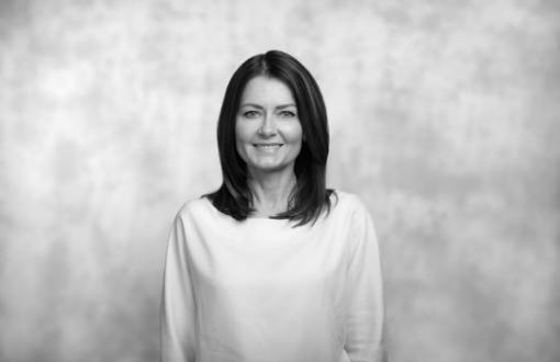 czarnobiały portret kobiety uśmiechniętej, w ciemnych włosach