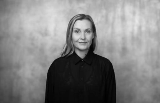 czafrno biały portret kobiety dojrzałej, uśmiechniętej, w czarnej kurtce i z kręconymi włosami długości do ucha